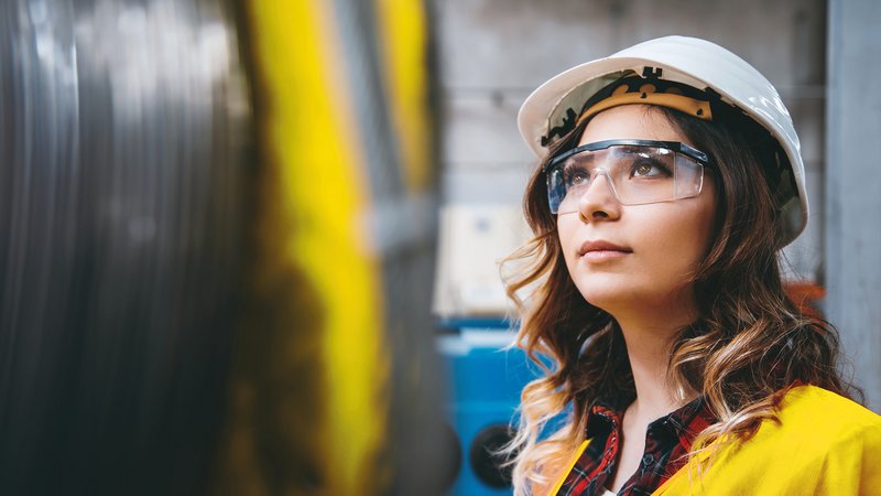Frau im Lager mit Helm und Schutzbrille Frau im Lager mit Helm und Schutzbrille, aufschauend nach links oben